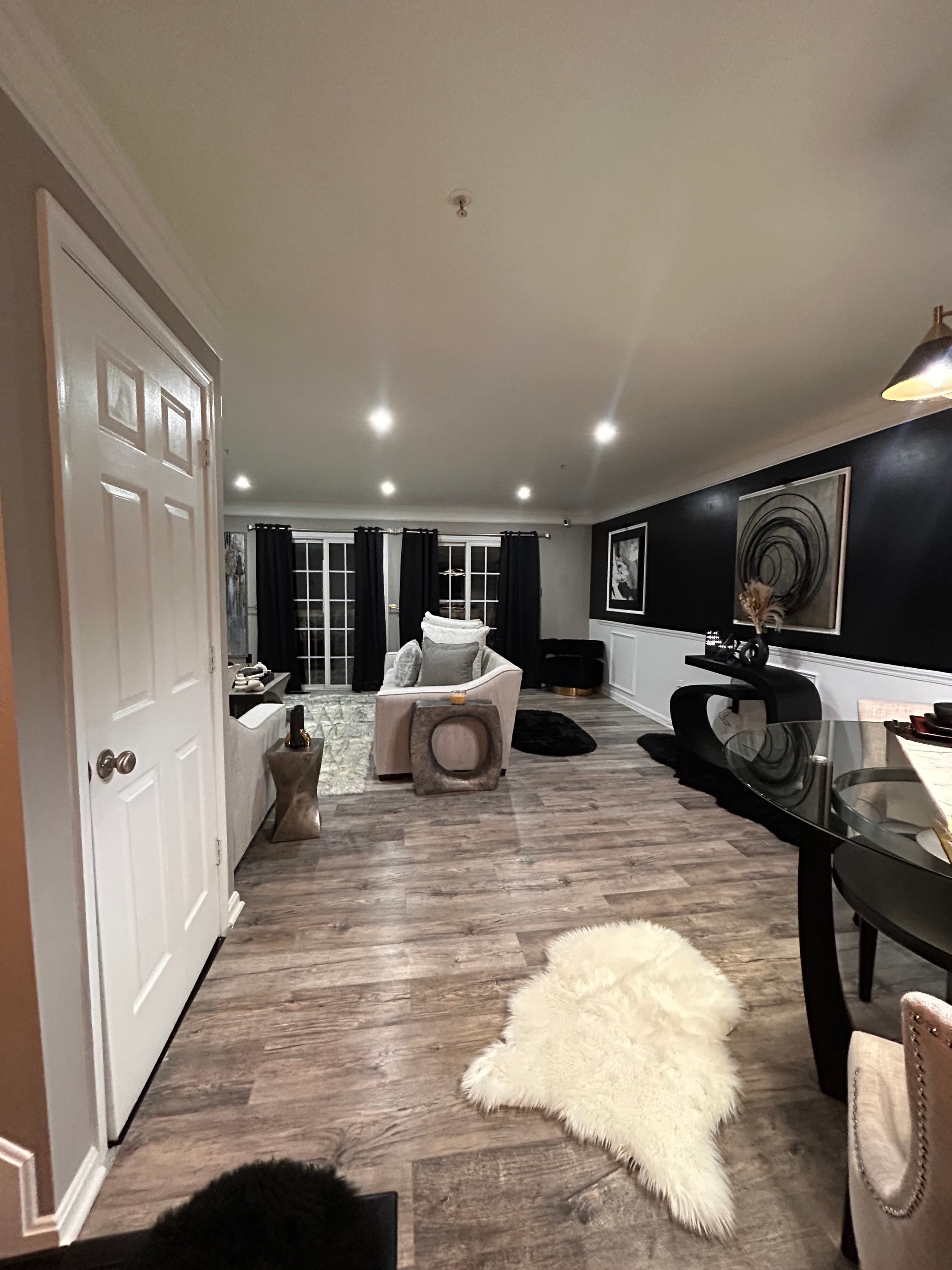 Modern living room featuring black accent wall, grey sofa, and a white faux fur rug.